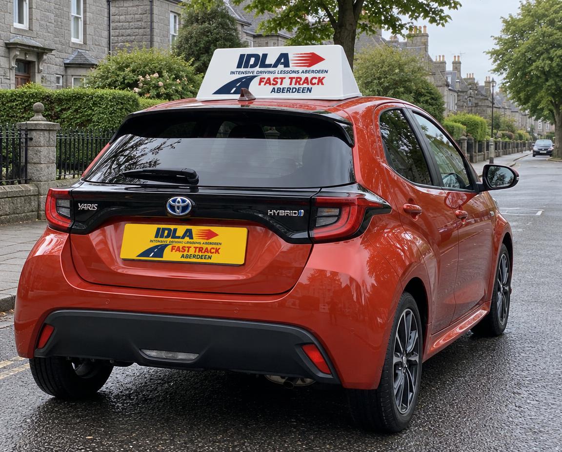 Red Toyota Yaris Hybrid with IDLA Fast Track rooftop sign on a residential Aberdeen road
